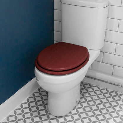 Mahogany soft-close tongue and groove MDF wood toilet seat showing seat in place on a white ceramic toilet